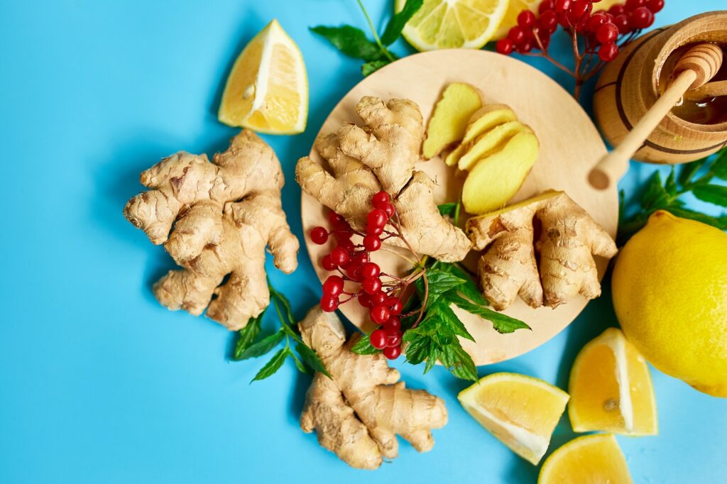 Flat lay of Immune boosting remedy, immunity boosting foods ginger, lemon,  honey,  guelder rose, mint on blue background Top view, copy space