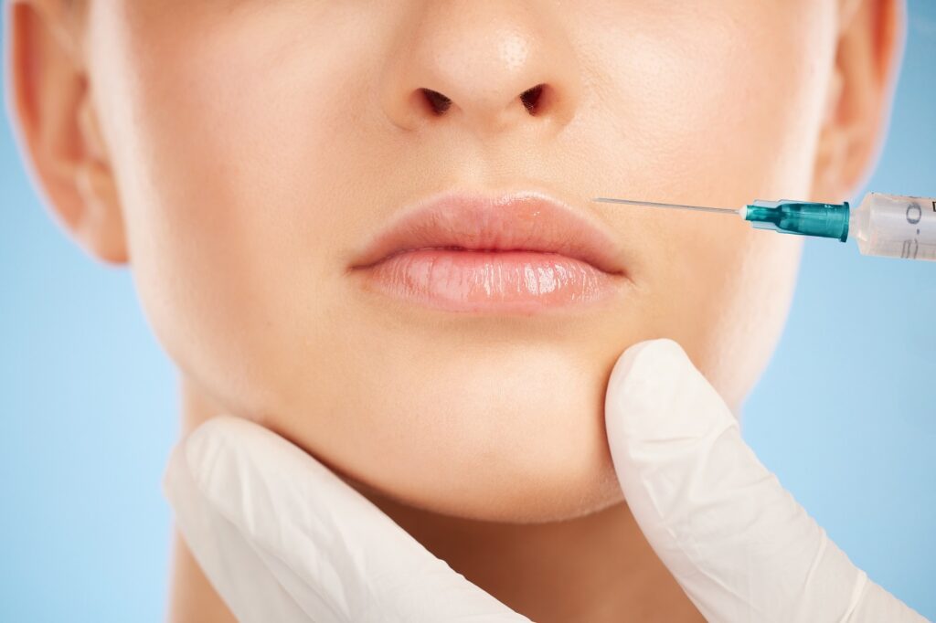 Botox, facial and lip filler by woman with cosmetic injection isolated against a studio blue backgr.